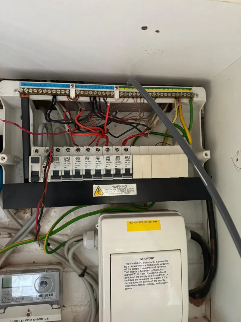 Electrical fuse box with wires and labels.