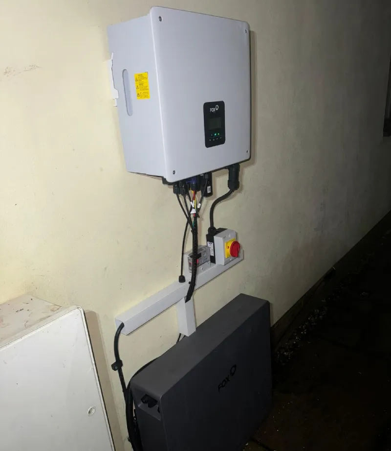 Wall-mounted solar inverter with connected cables.